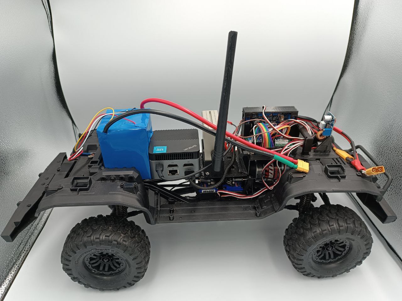 Open RC car with battery, mini PC, LTE antenna, controller and power wiring installed on the chassis